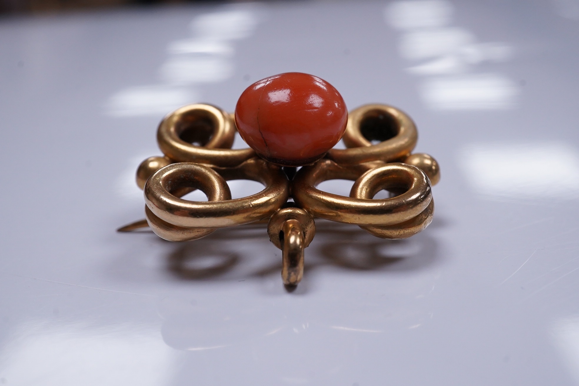 A yellow metal and coral bead set scrolling brooch, 31mm, gross weight 13 grams. Condition - poor